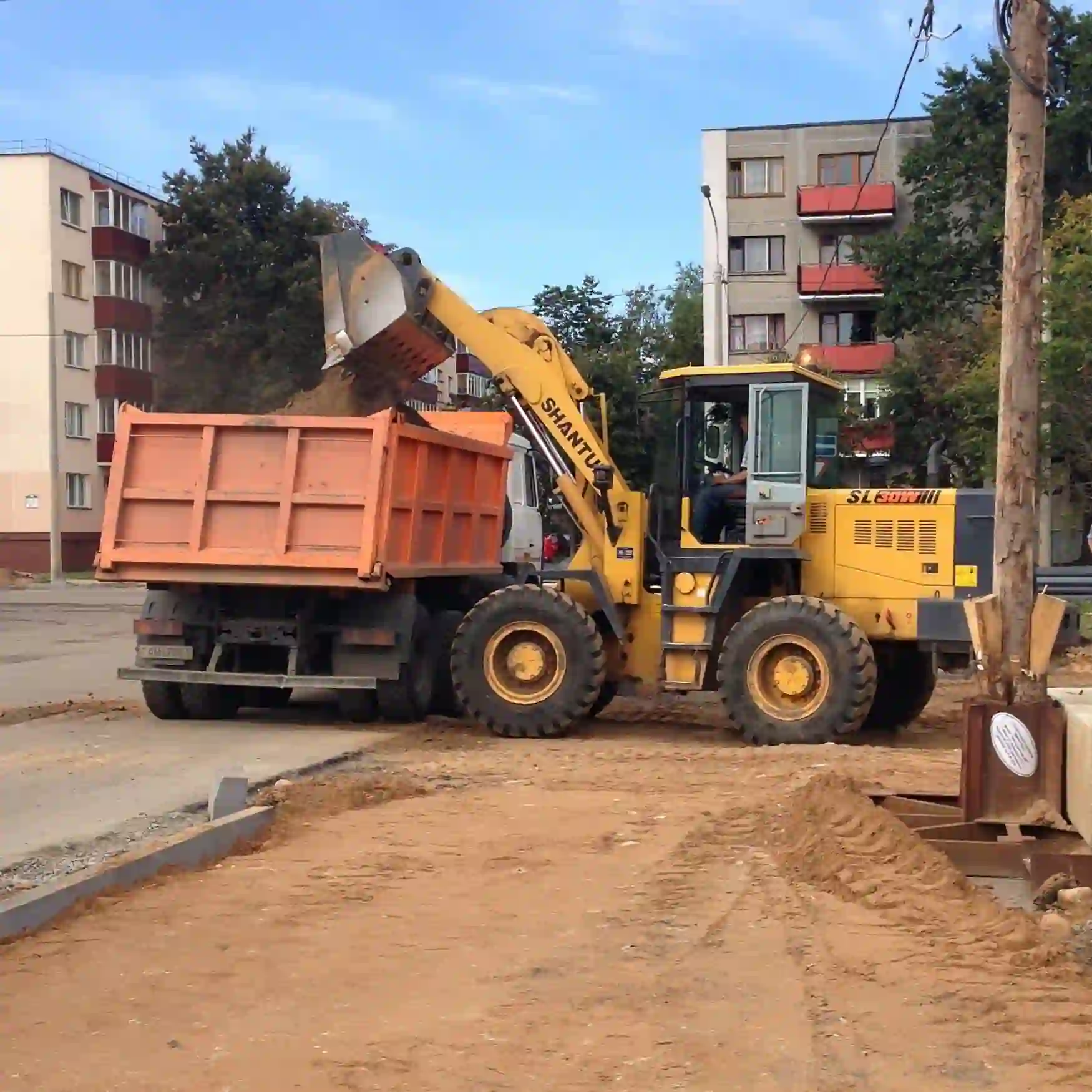 Погрузка грунта фронтальным погрузчиком в самосвал для вывоза с объекта