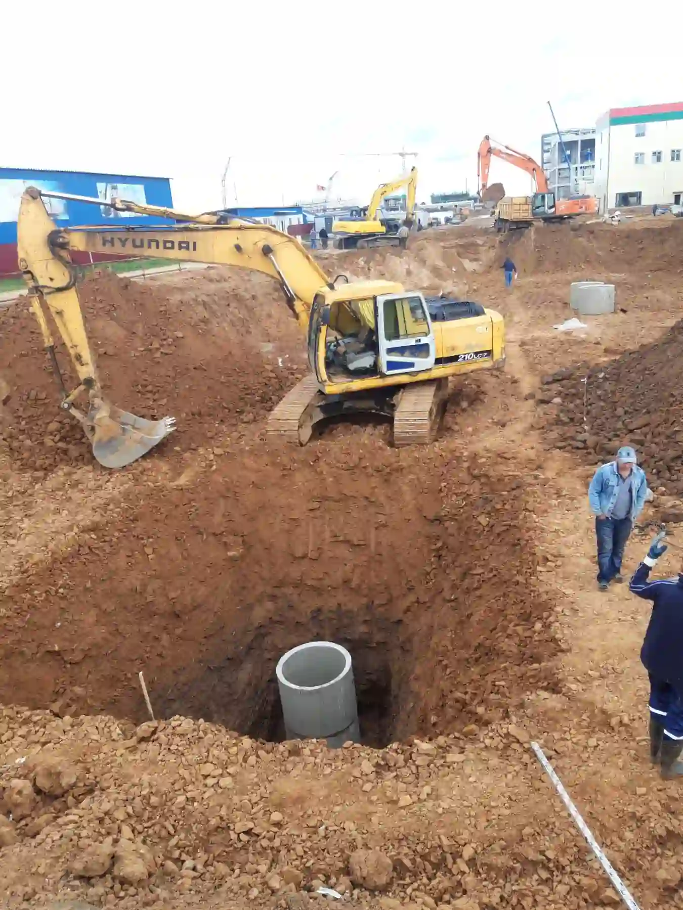 Разработка котлована под железобетонный колодец инженерных сетей гусеничным экскаватором на строительной площадке